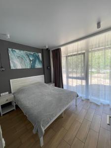 ein Schlafzimmer mit einem Bett und einem großen Fenster in der Unterkunft Золотой Бугаз, Колоски, апартамент 7/1 in Karolino-Buhas