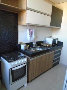 a small kitchen with a stove and a sink at Apartamento Temporada D'Loren dos lagos 4º andar in Capitólio