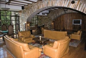 a living room with leather furniture and a stone wall at La Rectoral in Taramundi