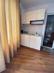 a kitchen with white cabinets and a wooden floor at Guest House Kostovi in Kiten