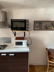 a kitchen with a microwave and a tv on a counter at Au Cheval Blanc - appartements et chambres d'hôtes in Albertville