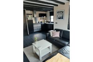 a living room with a black couch and a white table at Zomerhuis Adriana in Egmond aan Zee