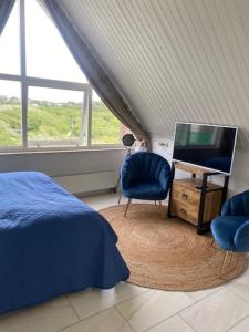 Schlafzimmer mit einem Bett, einem TV und einem Stuhl in der Unterkunft Huize de Duinen in Bergen aan Zee