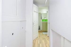 eine weiße Küche mit weißen Schränken und Holzböden in der Unterkunft TMS Spacious 4 bedroom house! Free Parking! Crosby Dagenham! in Dagenham