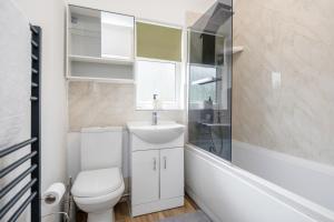 a white bathroom with a toilet and a sink at Everything You Need I Super Comfy I Sleeps 7 I WiFi I Parking I 4BDR in Dagenham +15 photos