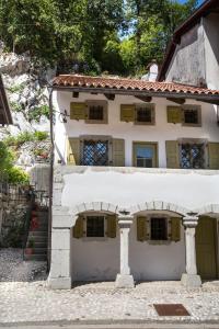 a white house with green shutters on the side at Hiša Liza in Kobarid