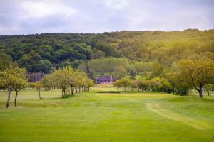 a green field with trees and a house in the distance at Äppelgårdens Golfklubb in Båstad