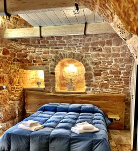 a bedroom with a blue bed in a stone wall at Trulli e Puglia Resort in Alberobello