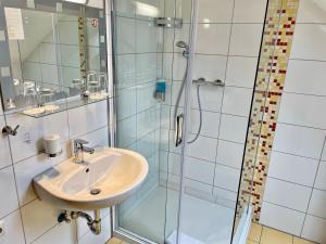 ein Bad mit einem Waschbecken und einer Dusche in der Unterkunft Hotel Zum Ritter in Seligenstadt