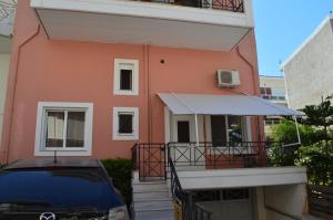 a car parked in front of a pink building at Anastasias Apartment center City by Dimitropoulos in Aigio