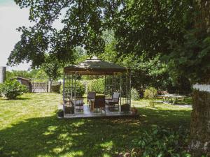 un gazebo con sedie e un tavolo in un cortile di LA LAUJÈRE Chambres d'hôtes ROMANCE a La Caillère