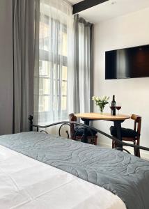 a bedroom with a bed and a table and a tv at Copernicus Street Apartment - Broken Flowers and Twin Peaks in Toruń