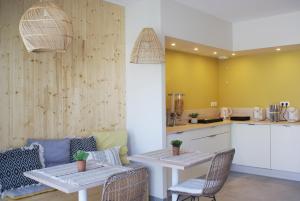 two tables and chairs in a kitchen with yellow walls at La maison du Potier in Valras-Plage