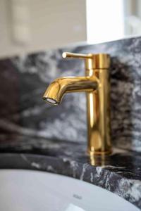 a gold faucet on a bathroom sink at DOMKI - Kaszuby Resort ZACISZE - new cottage in Chmielno