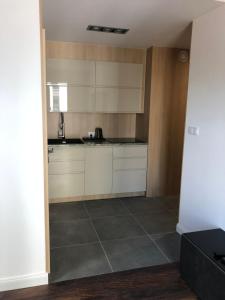 a kitchen with white cabinets and a tile floor at Apartamenty Platinex 3 in Krakow