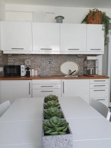 a kitchen with white cabinets and a table with a bunch of bananas at MANDARA WELLNES APARTMANOK in Siófok