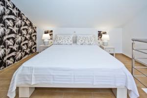 a bedroom with a large white bed and two lamps at Luxurious Apartments Maslina with Beach in Milna