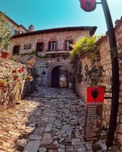 a narrow alleyway leads to a stone building with a clock on it at Hotel Klea in Berat