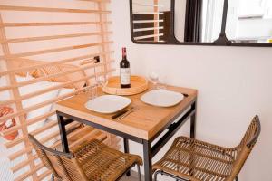 einen Tisch mit einer Flasche Wein und zwei Stühlen in der Unterkunft Studio de charme - calme, discret & cosy - 3' RER in Évry-les-Châteaux