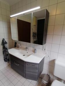y baño con lavabo, espejo y aseo. en Ferienwohnung DORO en Kelberg