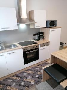 a kitchen with white cabinets and a stove top oven at Ferienwohnung DORO in Kelberg