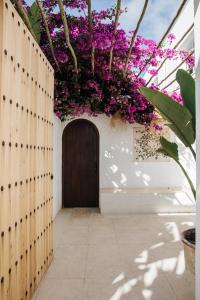 een deur in een muur met paarse bloemen bij La Bohemia del Rio Hostal Boutique-Adults Only in Santa Eularia des Riu