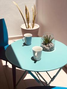 a blue table with two cups and a plant on it at Apartamentos Sunset Lanzarote in Tías