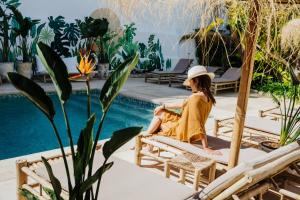 a woman sitting on a chair next to a pool at La Bohemia del Rio Boutique Hotel - Adults Only in Santa Eularia des Riu
