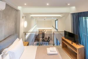 a bedroom with a bed with a television and a staircase at 3 DOORS VILLAS in Iraklitsa