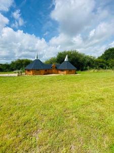 a wooden building with two domes in a field at Miniature oast house in Ash