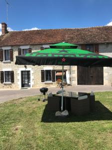 a green umbrella sitting in the grass next to a grill at Saint Vincent in Bué