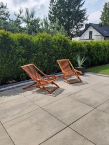 two wooden chairs sitting next to each other on a patio at Willa Piasutno z klimatyzacją in Świętajno