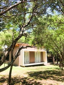 una pequeña casa en medio de un patio con árboles en Cabañas Acaciass en Los Cocos