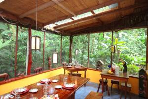 un comedor con 2 mesas y una ventana grande en Casa Rio Blanco Eco Friendly B&B, en Guápiles