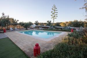 a swimming pool with a red fire hydrant in a yard at Herdade da Yucca - Retreat & Spa in Terena