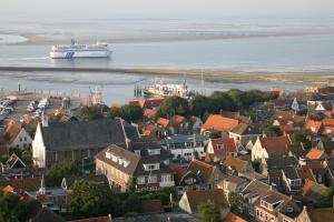 ein Kreuzfahrtschiff im Wasser in der Nähe einer Stadt in der Unterkunft Hotel Oepkes in West-Terschelling