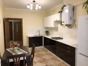 uma cozinha com armários pretos e uma mesa com uma sala de jantar em VIP Апартаменти Львів Сихів центр Червоної Калини em Lviv