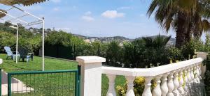 a white fence in a yard with a palm tree at Maison Margot in Vallauris