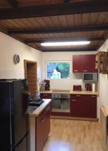 a kitchen with red cabinets and a black refrigerator at Ferienhaus Green Garden Berlin - Welcome to Berlin in Berlin
