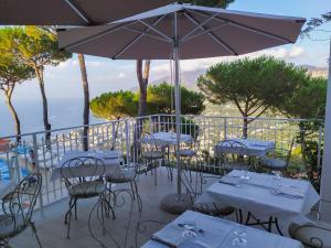 um restaurante com mesas e cadeiras e um guarda-sol em Hotel Villa Fiorita em Sorrento