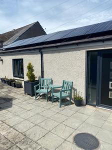 dos bancos verdes sentados en un patio con paneles solares en Beach Cottage, en Berwick-Upon-Tweed