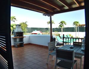 un patio con parrilla, mesa y sillas en Villa Raima, en Playa Blanca