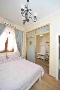 a bedroom with a white bed and a chandelier at BLISS HOUSE Oradea in Oradea