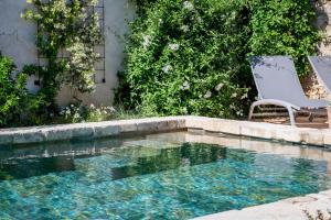 een zwembad met een stoel naast een huis bij Mas des Aïeux in Laudun