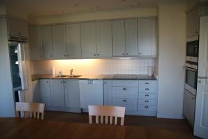 a kitchen with white cabinets and a table and chairs at Värmvik Gårdskontor in Västervik