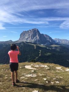 uma mulher tirando uma foto de uma montanha em Arya Alpine Lodge em Selva di Val Gardena