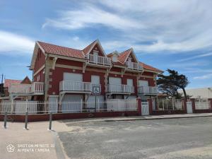 a red house with white balconies on a street at Joussac Côté Plage - Devant l'océan in Soulac-sur-Mer +20 photos