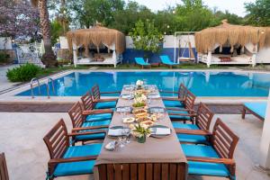a long dining table with chairs next to a swimming pool at B&B Boutique Hotel in Dalyan