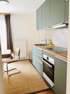 uma cozinha com armários azuis, um lavatório e uma cadeira em urbanAPARTMENT No.1 Memmingen em Memmingen