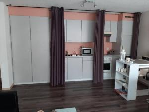 a kitchen with white cabinets and purple curtains at Jac-Cosy in Fleurier